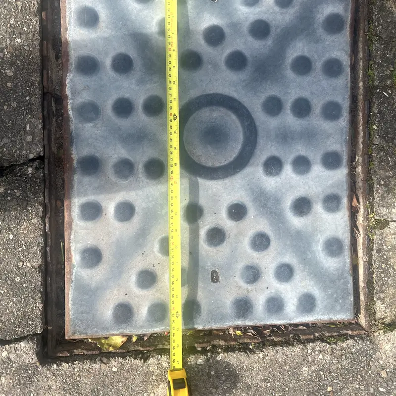 A cast iron drain cover measured with a tape before ordering a replacement frame