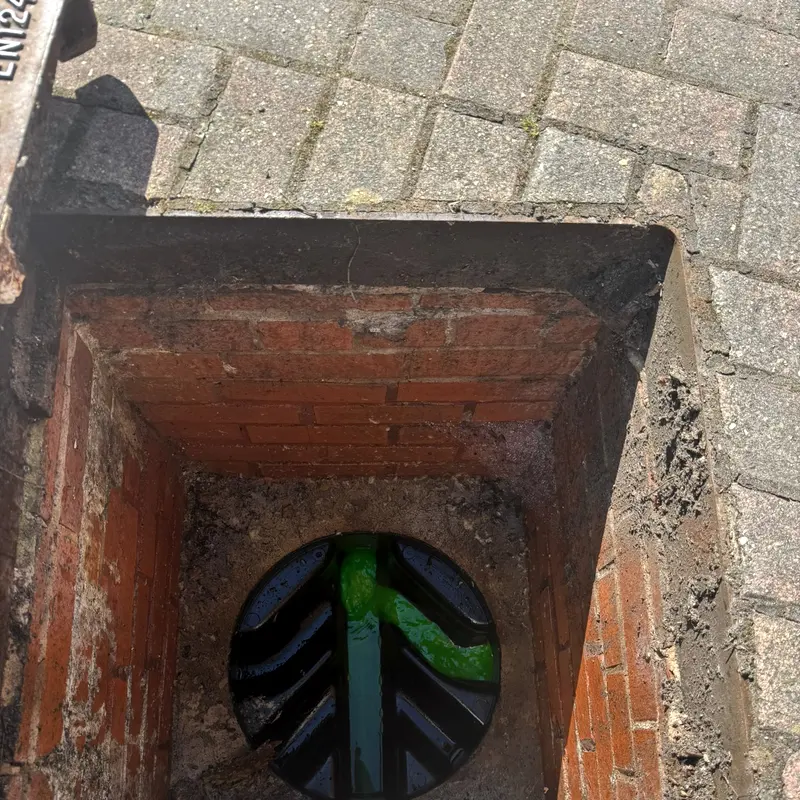 Green tracer dye running through the channel of the same manhole